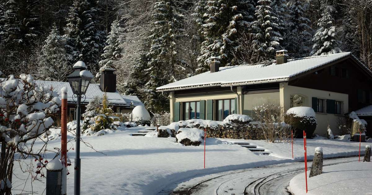 Snötäckt villa med plogad uppfart och snökäppar en vinterdag
